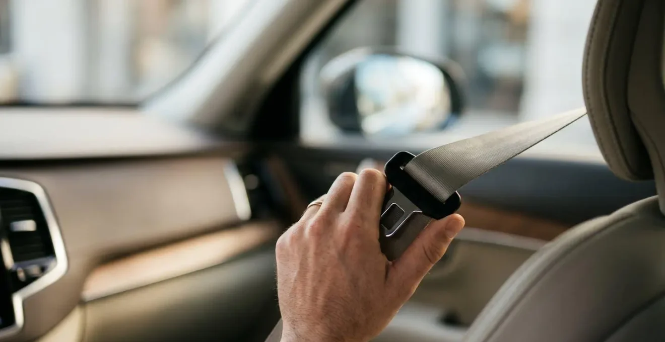 Vue rapprochée d'une main attachant une ceinture de sécurité moderne dans un habitacle automobile, symbolisant la protection et la responsabilité