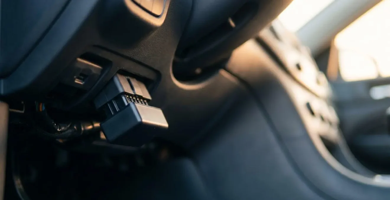 Boîtier de diagnostic OBD-II connecté au port d'un véhicule avec éclairage tamisé