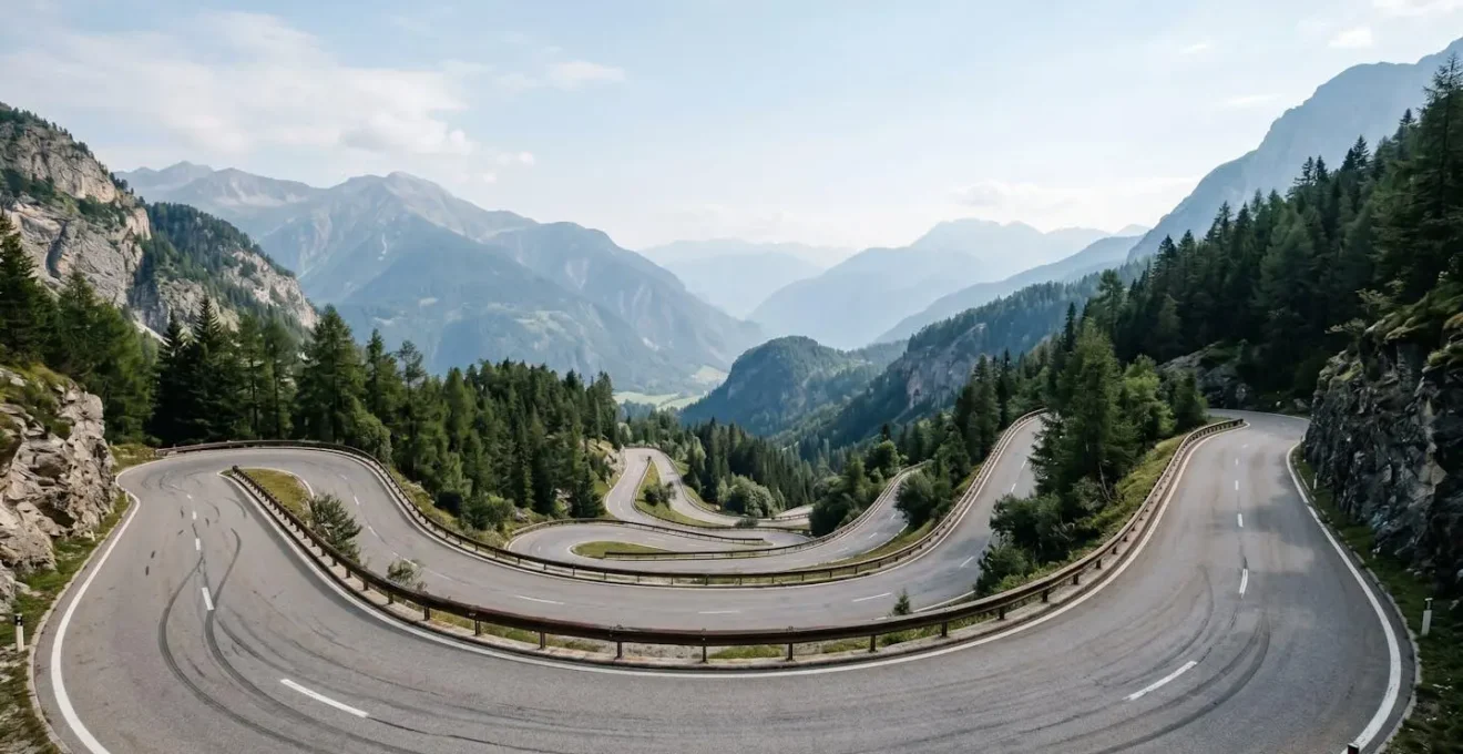 Vue panoramique d'une route de montagne sinueuse en descente illustrant les conditions de freinage intensif nécessitant une technique préventive