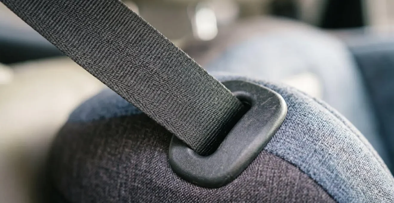 Gros plan sur un siège réhausseur pour enfant montrant le système de guidage de la ceinture de sécurité, illustrant la protection des jeunes passagers