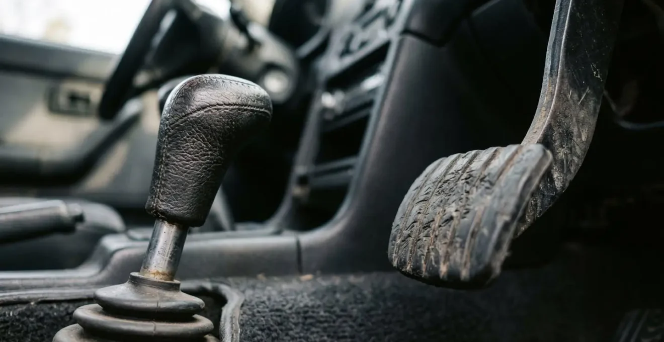 Gros plan sur pédale d'embrayage et levier de vitesses dans habitacle automobile avec lumière naturelle
